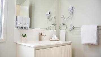 Un bany amb un lavabo, mirall, paraigua i assecador de cabells.