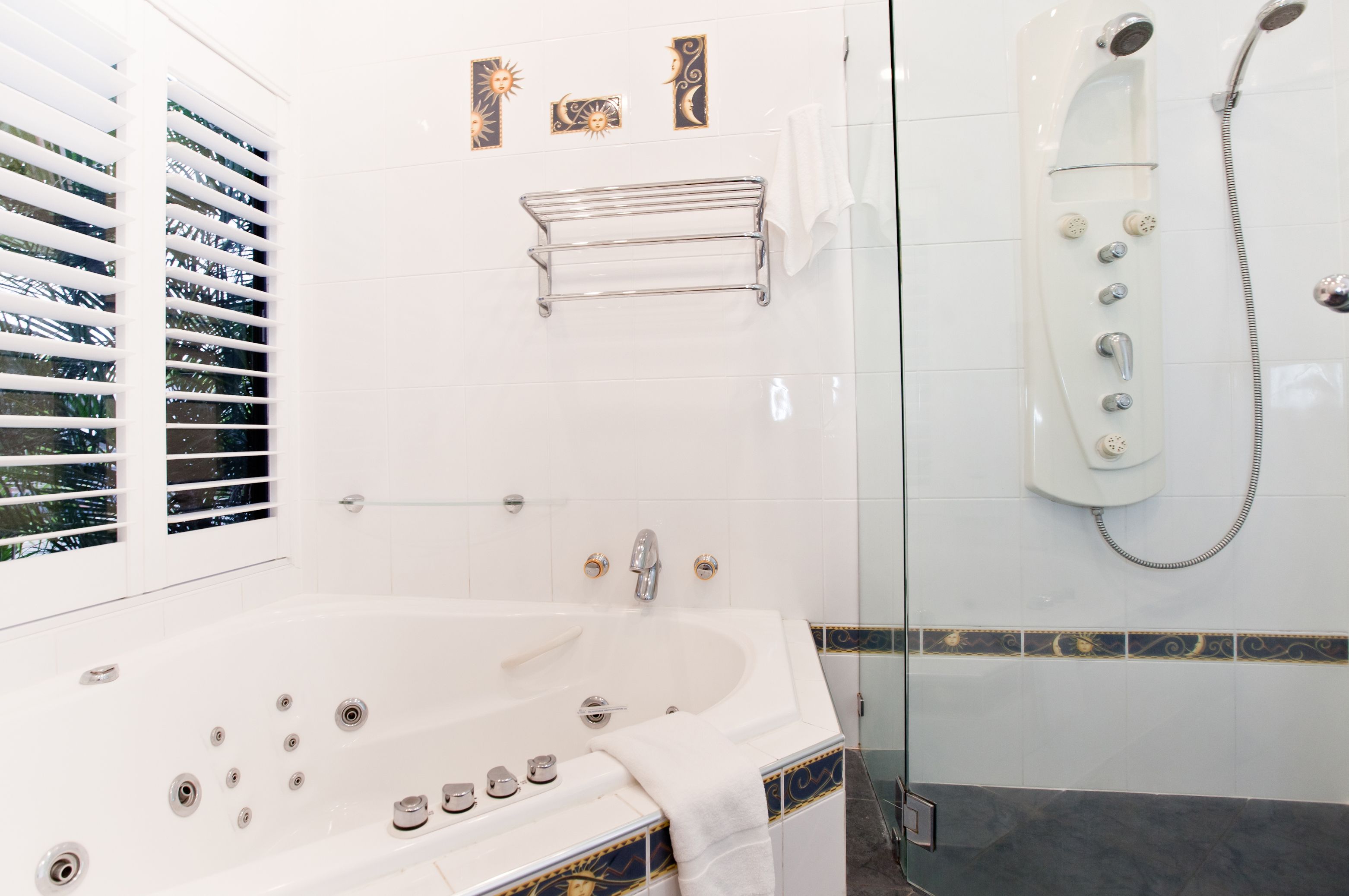 A modern bathroom with a large bathtub, a glass-enclosed shower, and decorative wall tiles.