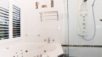 A modern bathroom with a large bathtub, a glass-enclosed shower, and decorative wall tiles.