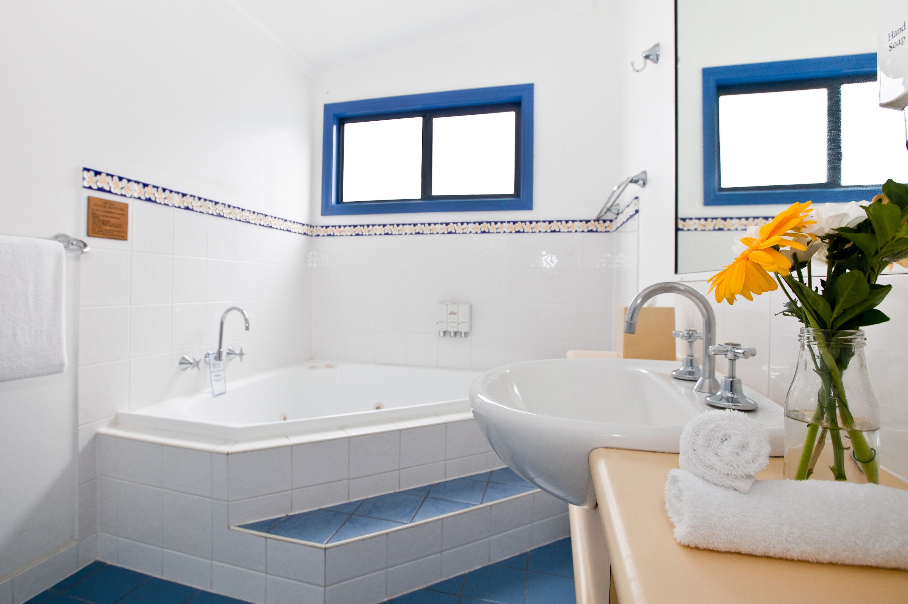 A bathroom with a bathtub, sink, and a window with blue trim.
