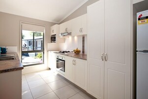 A modern kitchen with white cabinetry, a gas stove, and a built-in oven.