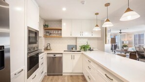 A modern kitchen with white cabinetry, stainless steel appliances, and pendant lighting. - La Grande Apartments Broadbeach (Broadbeach)