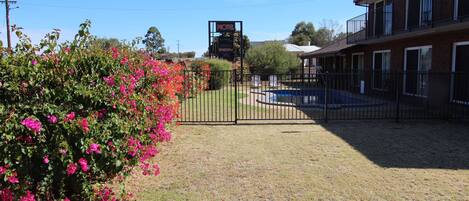 A motel with a fenced parking area, a signboard, and a building with multiple windows and balconies.