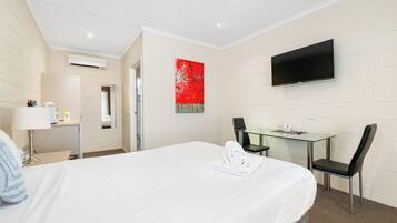 Une chambre d’hôtel avec un lit, un bureau, une chaise, une télévision et un tableau abstrait rouge accroché au mur.