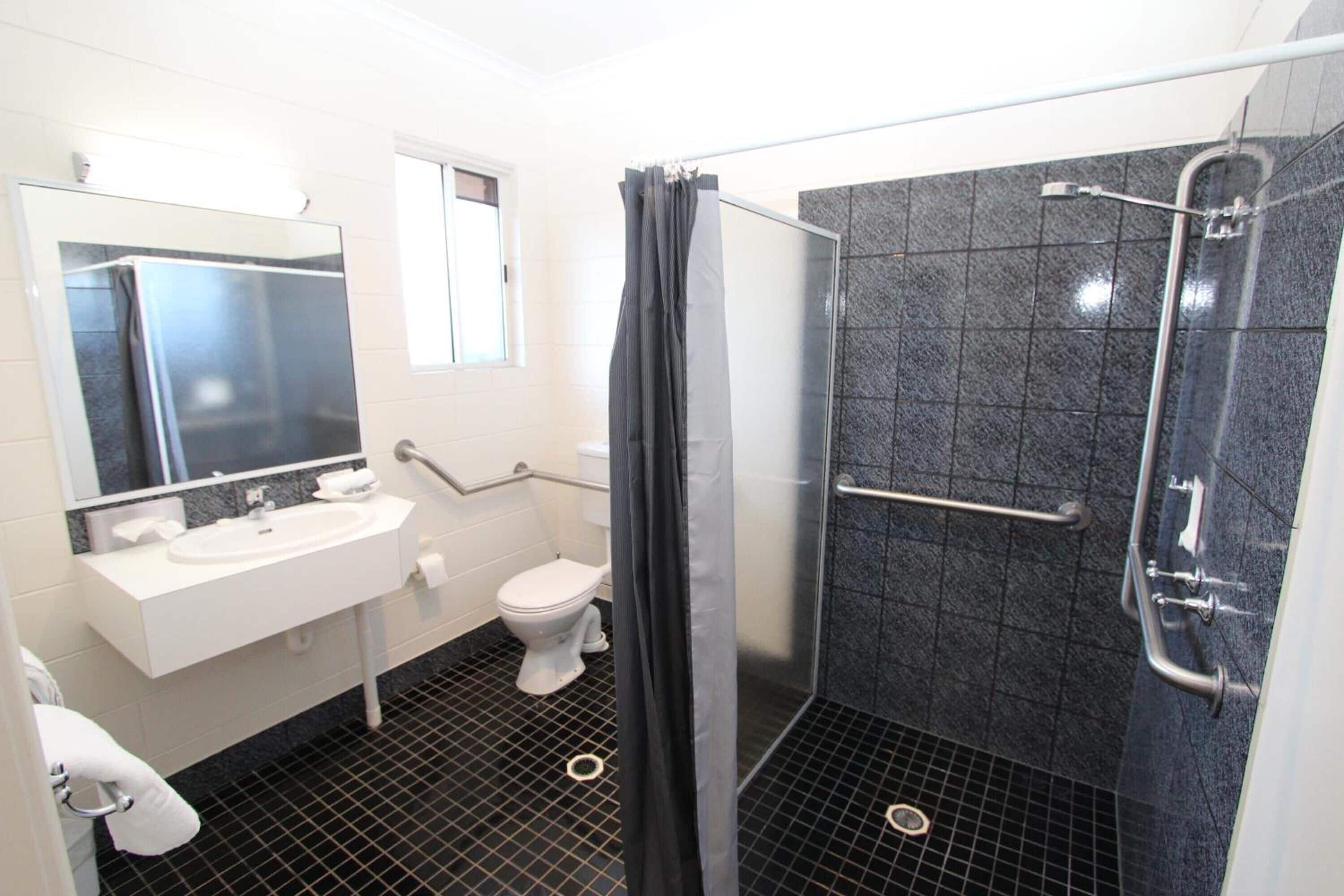 Ein modernes Badezimmer mit Waschbecken, Toilette und einer Duschkabine aus Glas.