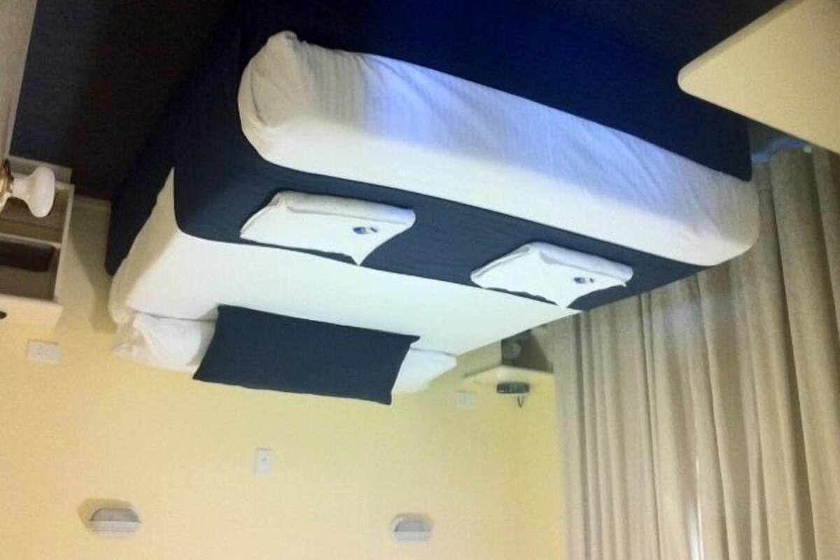 Una cama con cabecera oscura y dos mesitas de noche con lámparas.