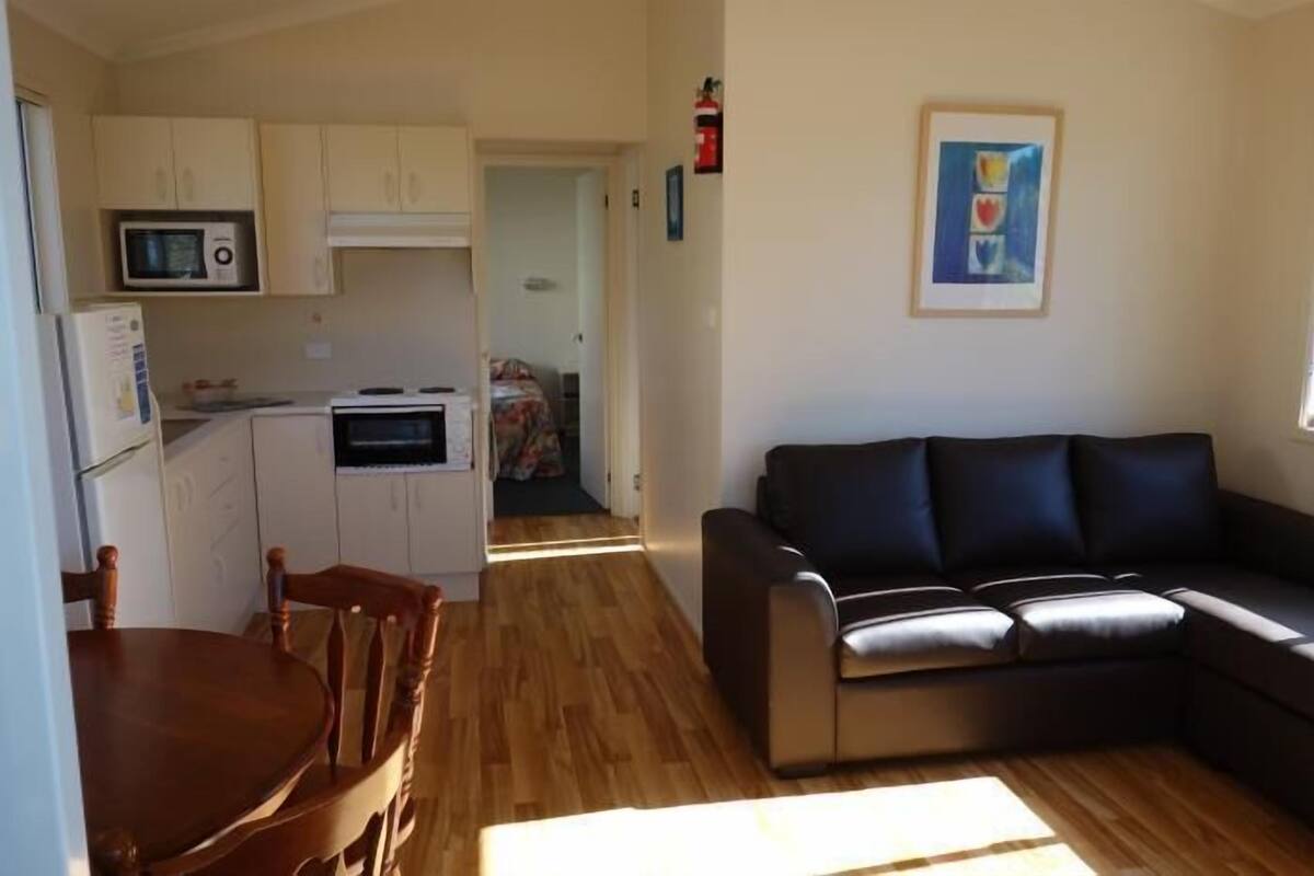 Un espacio habitable compacto con kitchenette, comedor y zona de estar.