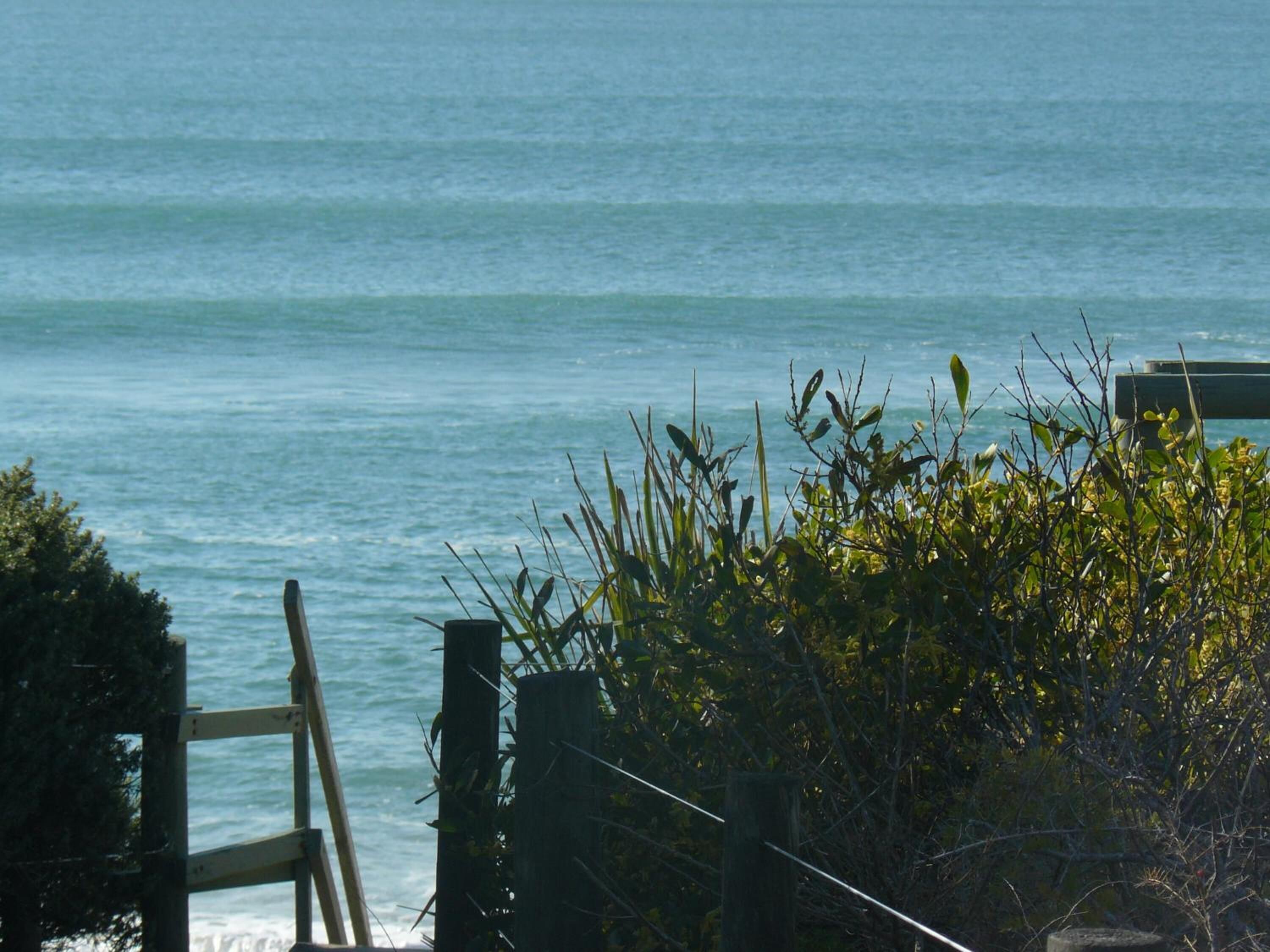 A wooden fence with a view of the ocean.