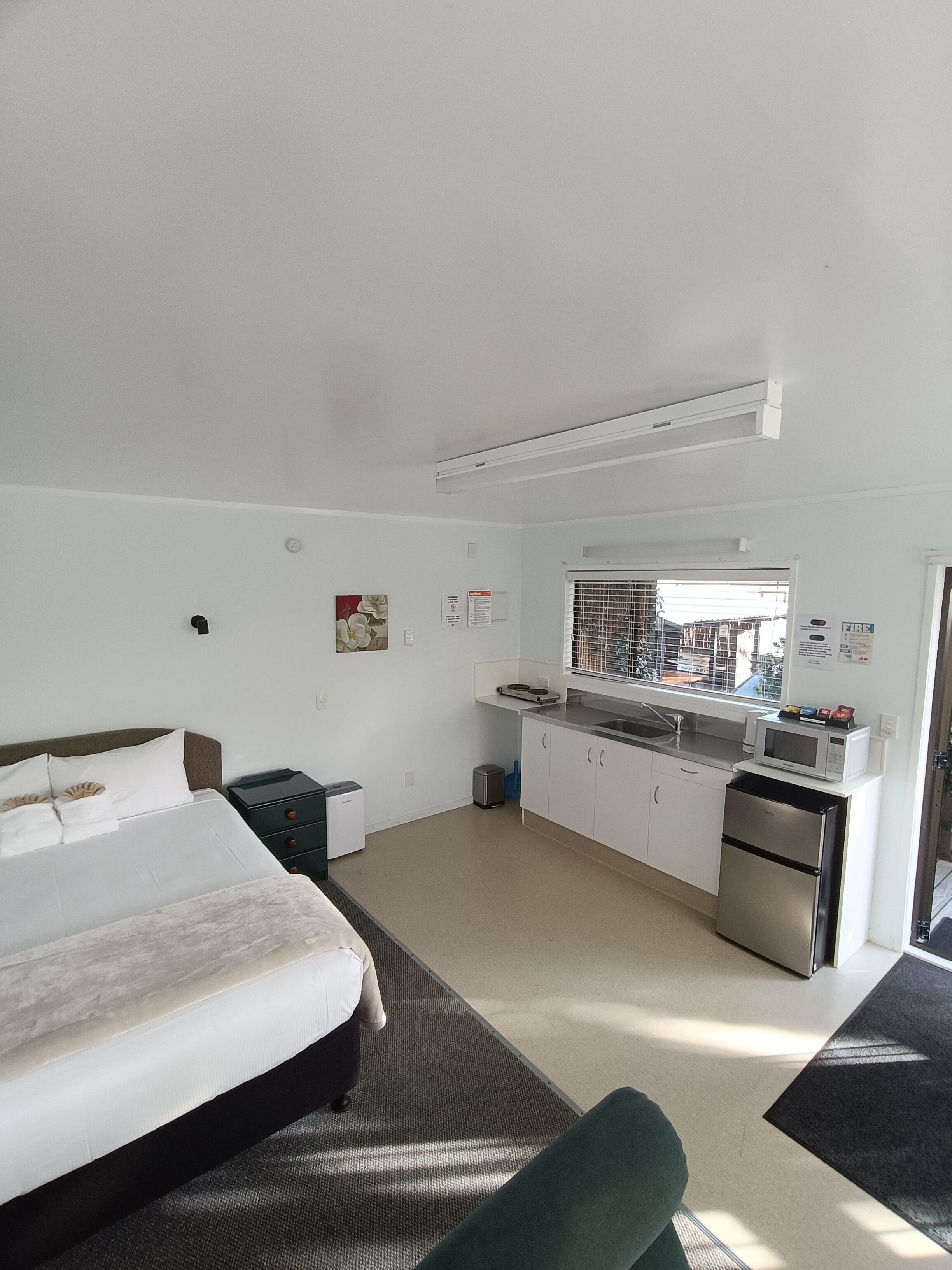 Une chambre d’hôtel avec un lit, une petite kitchenette et une fenêtre.