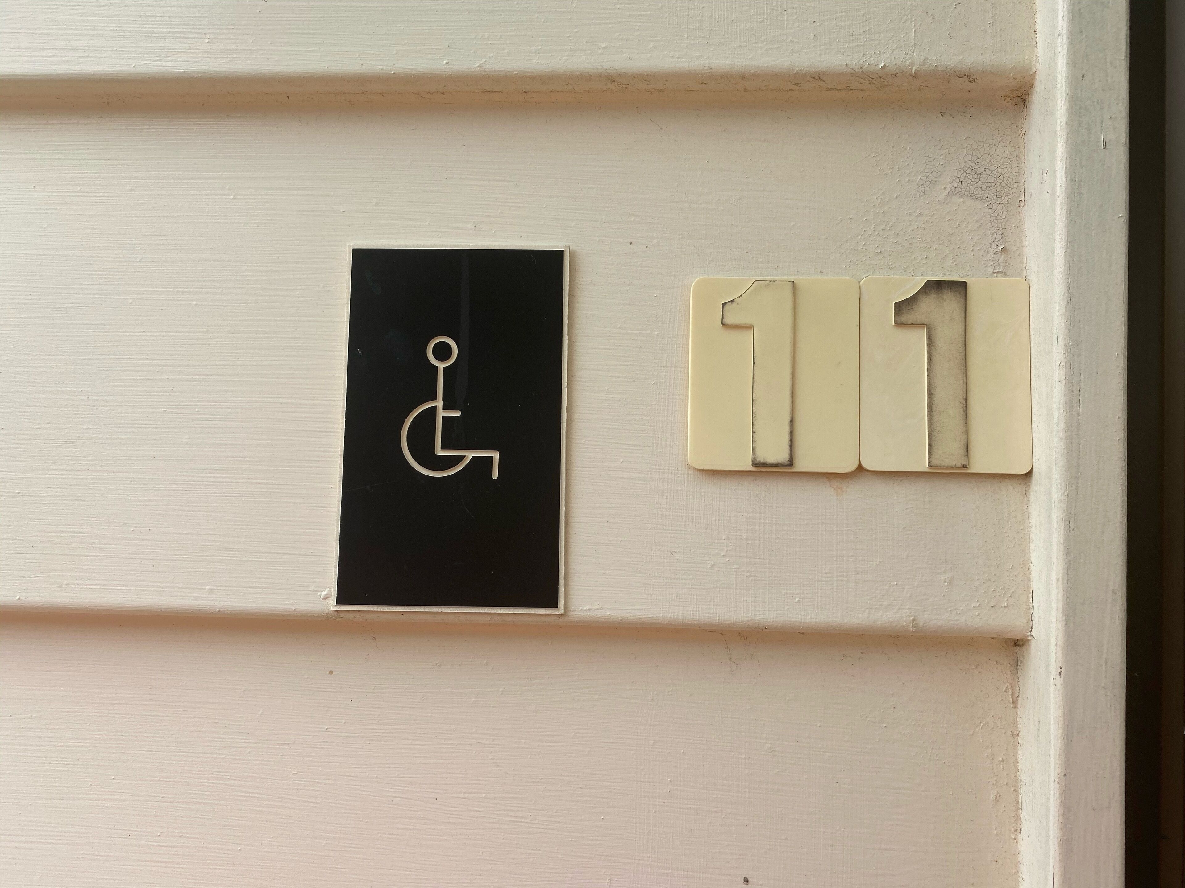 A door with a wheelchair accessibility sign and a room number sign.