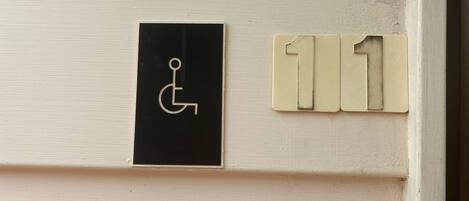 A door with a wheelchair accessibility sign and a room number sign.