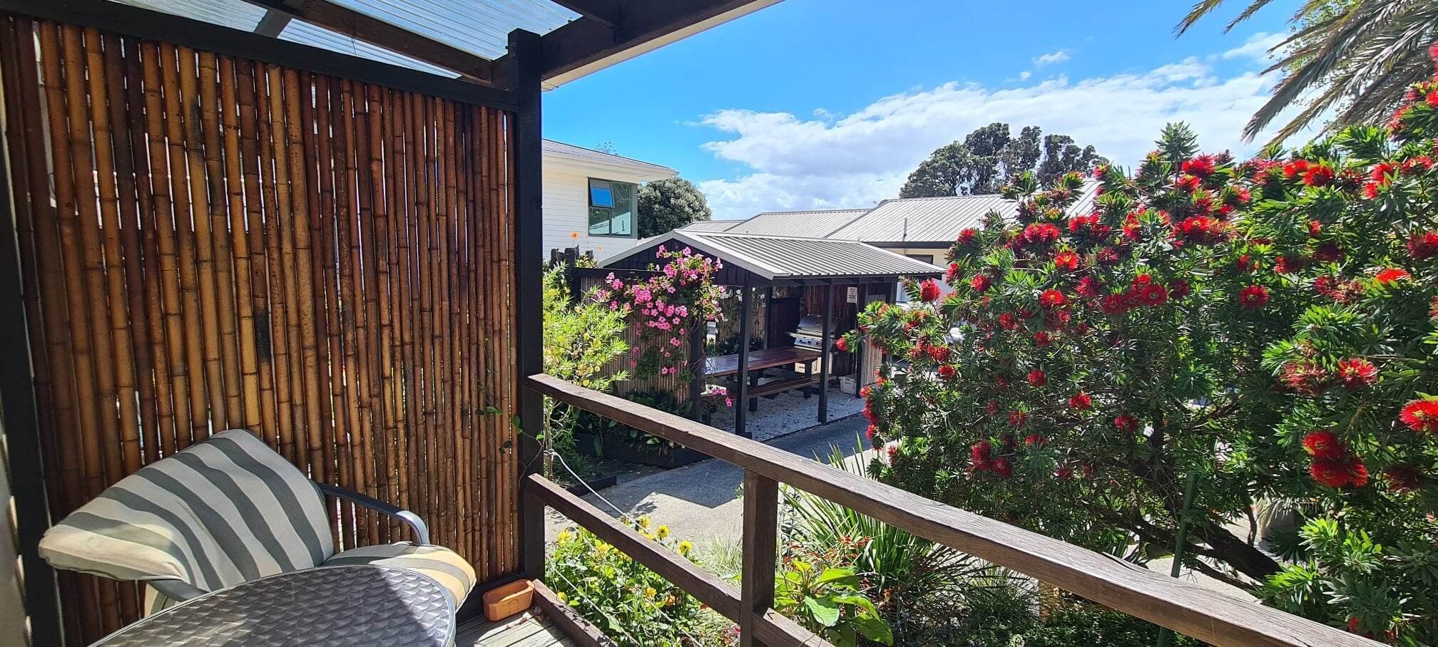 A balcony with a view of a garden and a building with a sloped roof.