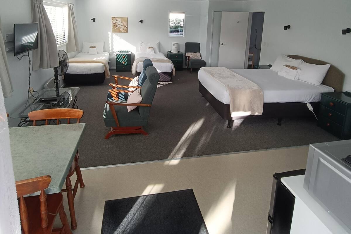 Une chambre d’hôtel avec un lit, un bureau, une chaise, une télévision et une fenêtre.