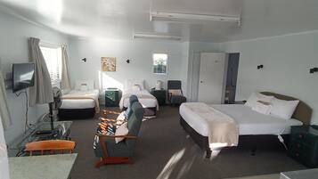 A hotel room with a bed, a desk, a chair, a TV, and a window.