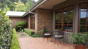 A brick house with a patio, two chairs, and a potted plant. - Yallambee (Bundanoon)