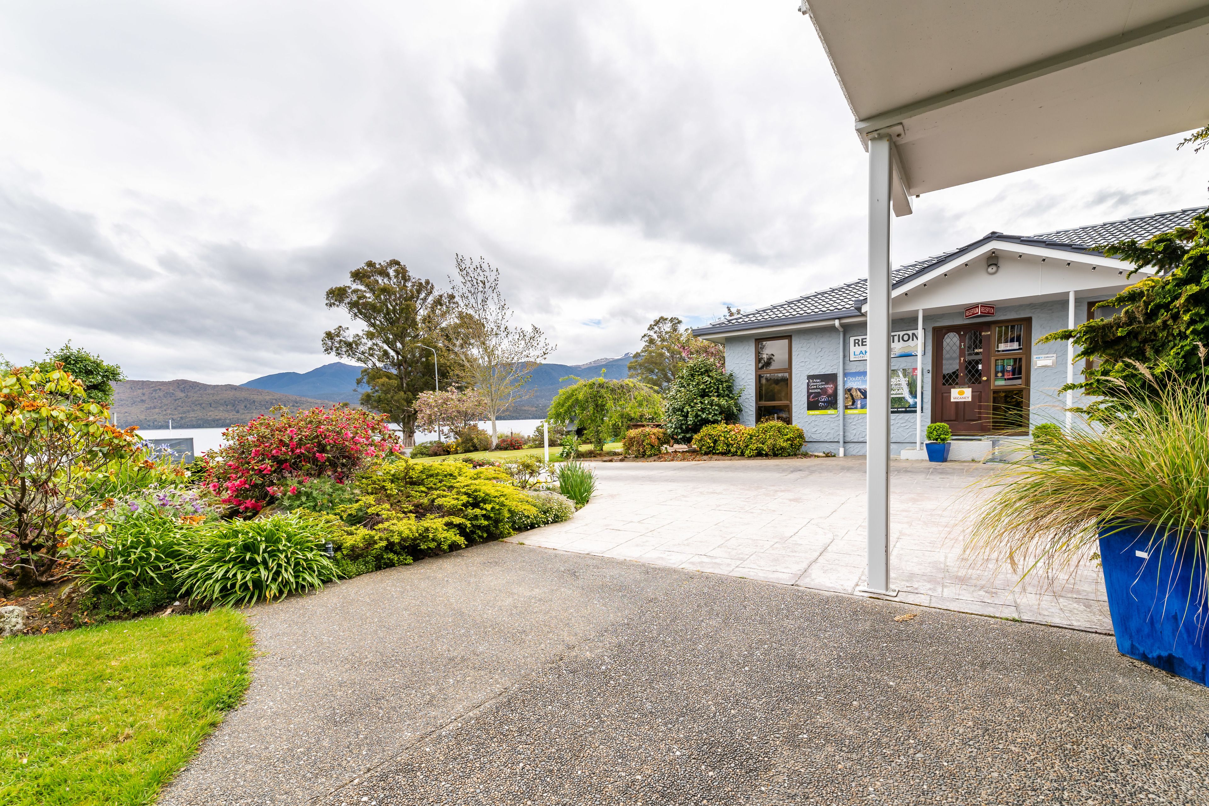 A building with a covered entrance, surrounded by landscaped gardens and a view of mountains.