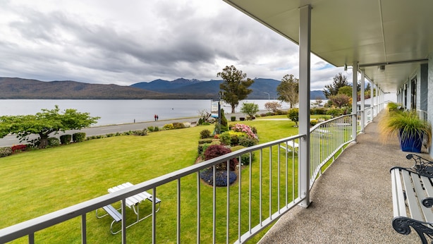 A covered balcony with a view of a lake and mountains. - Lakeside Motel & Apartments (Te Anau)
