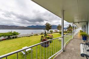 A covered balcony with a view of a lake and mountains. - Lakeside Motel & Apartments (Te Anau)