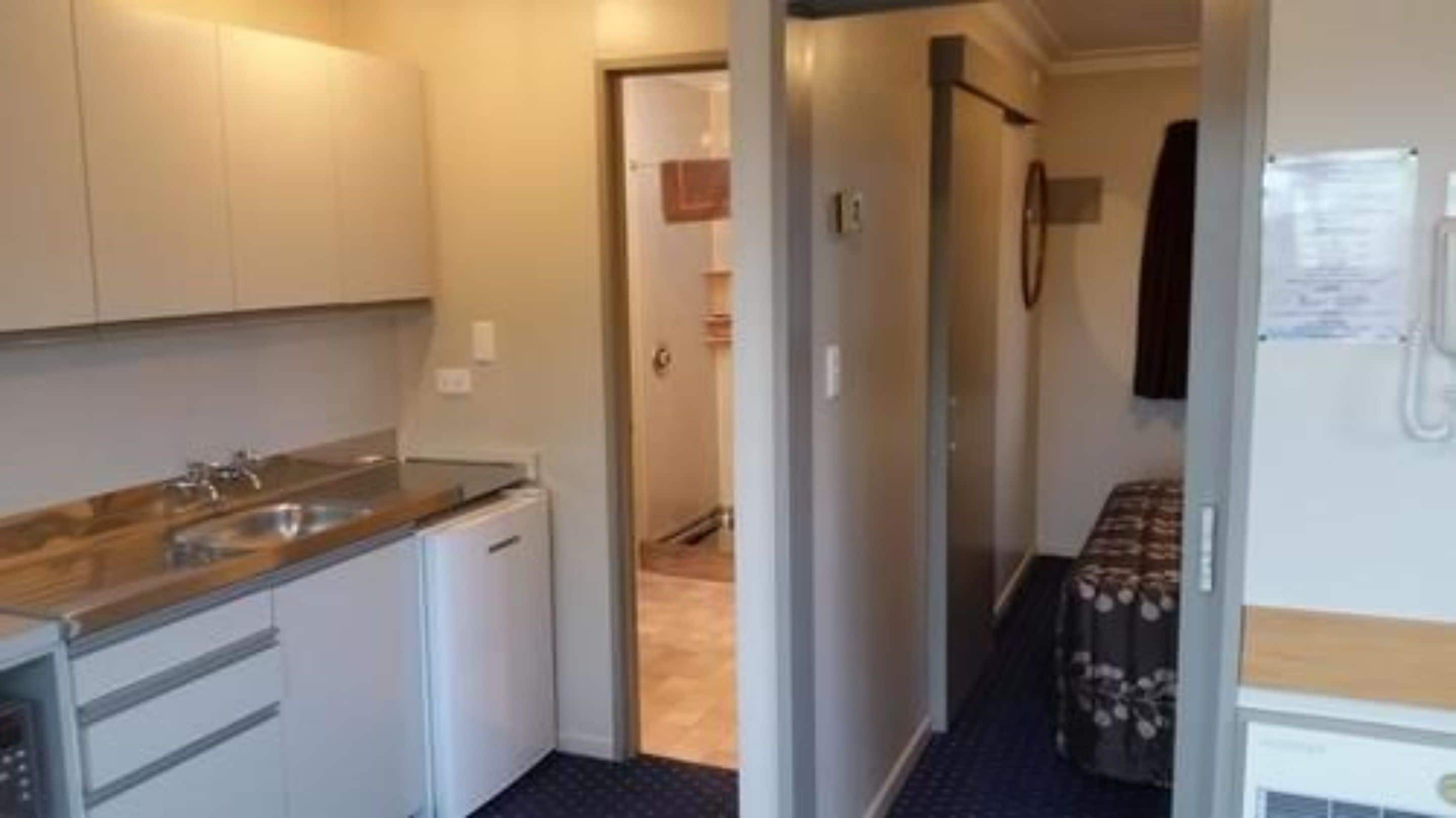 A compact kitchen with a sink, stove, and cabinets.