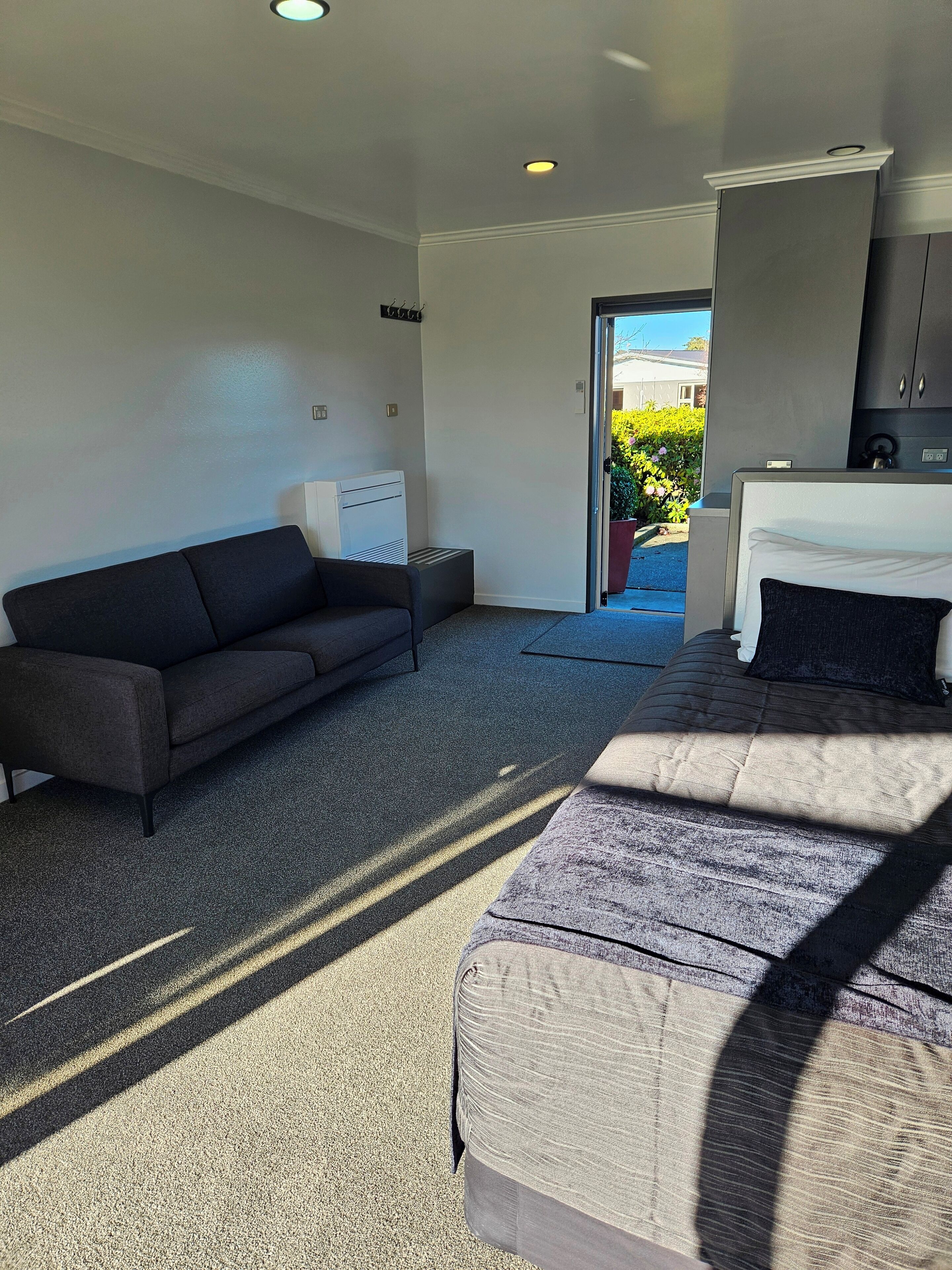 Ein modernes Hotelzimmer mit einer Couch, einem Bett, einem kleinen Tisch und einer fest installierten Heizung.
