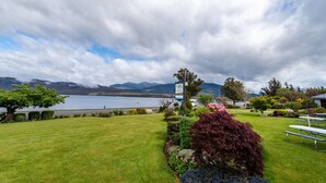 A lakeside view with a picnic area, a sign for 'Lakeview Resort', and mountains in the background. - Lakeside Motel & Apartments (Te Anau)