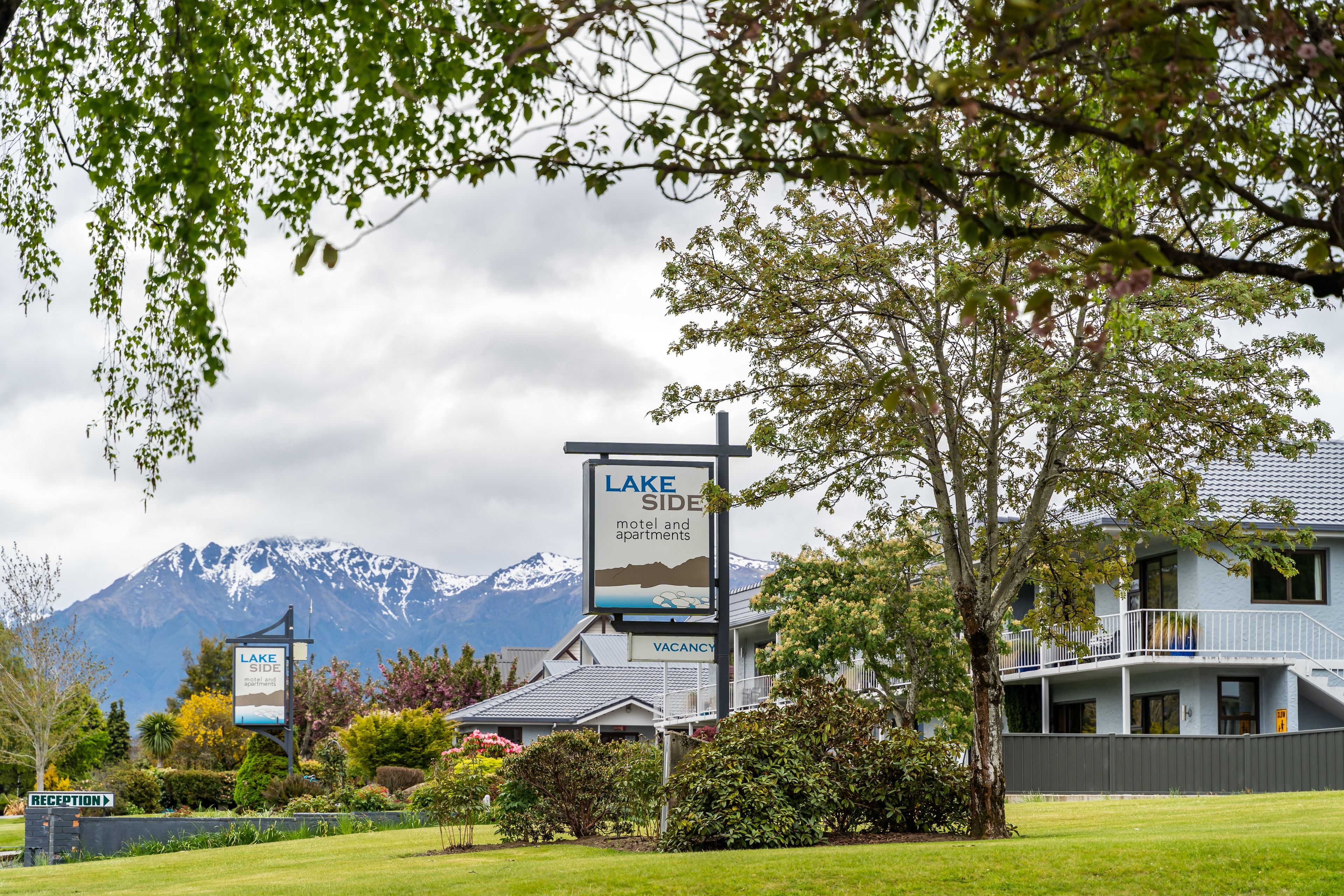 Een hotel genaamd 'Lake Side' met een bord waarop 'motel en appartementen' en een 'VACANCY' bord staat.