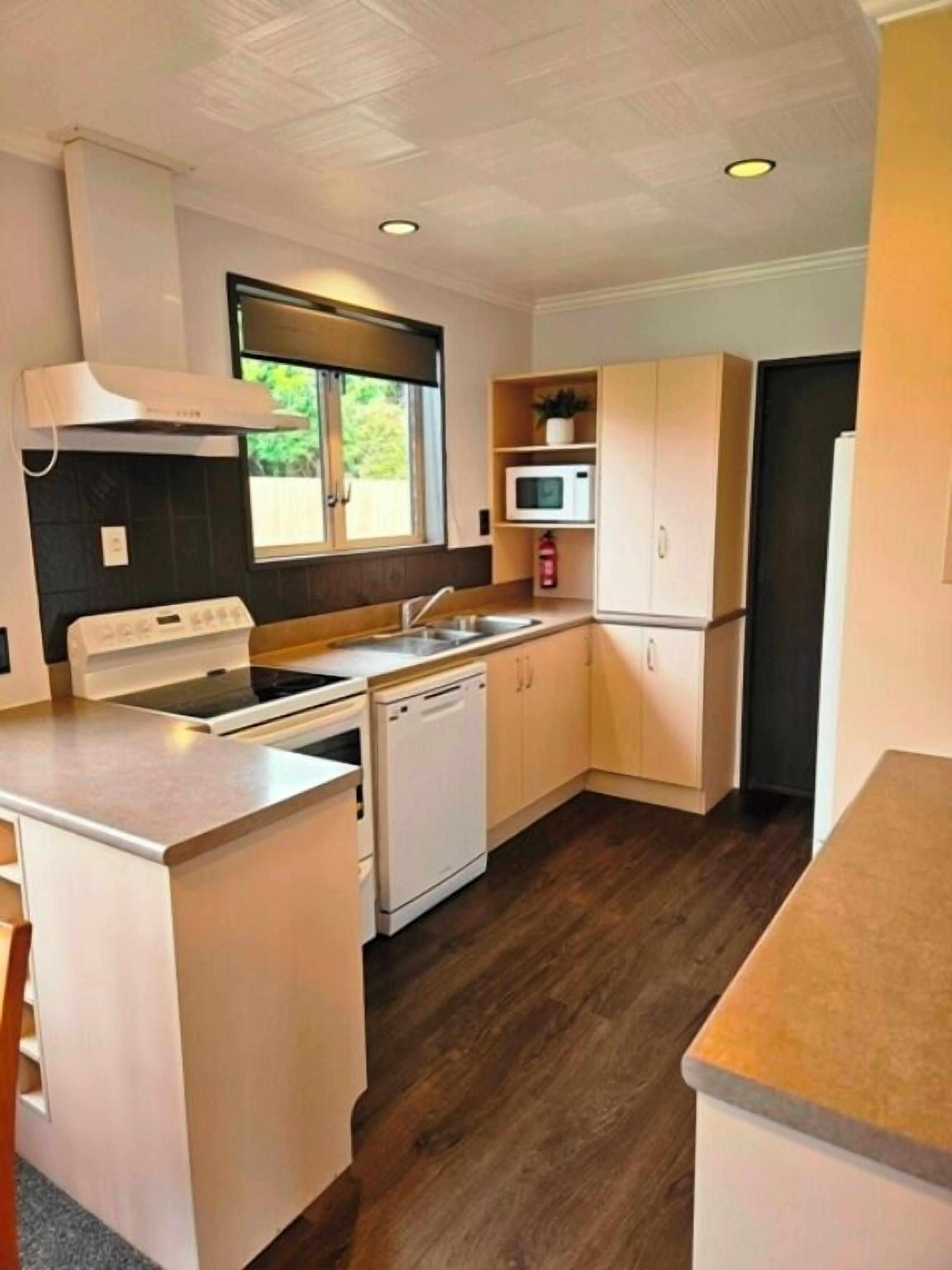 A compact kitchen with a stove, microwave, and dishwasher.