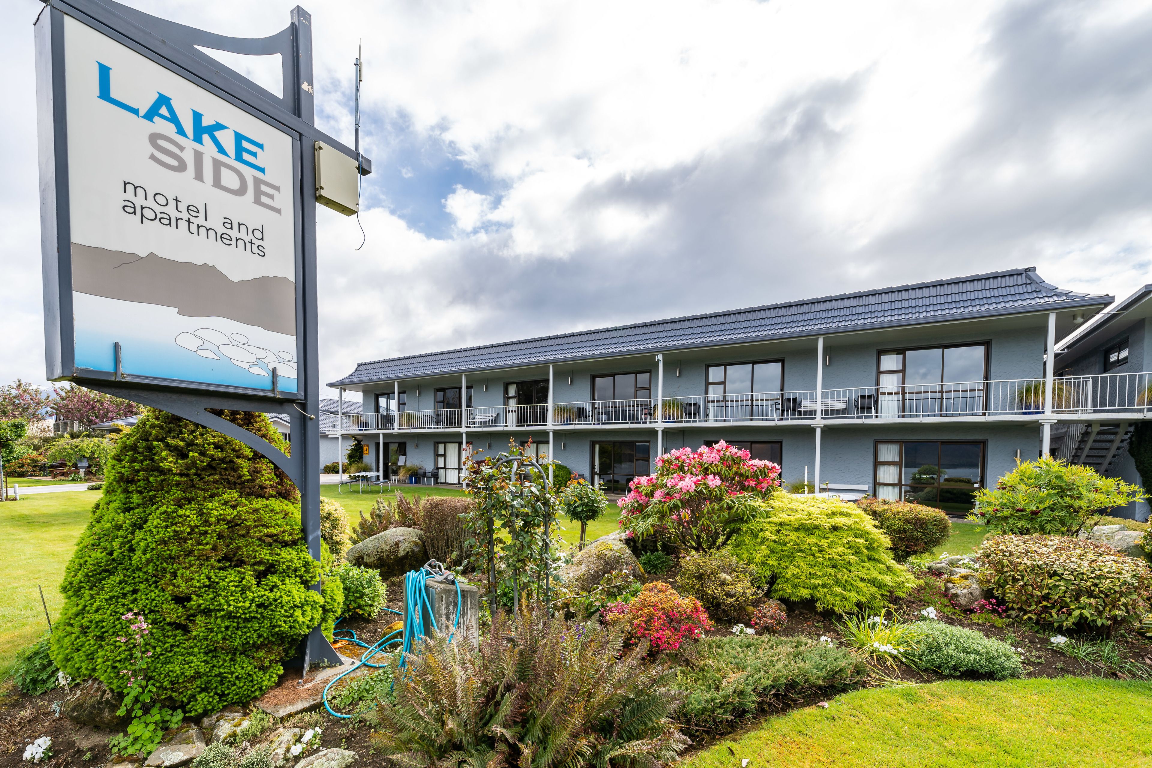 A motel with a signboard, multiple floors, and a well-maintained garden.