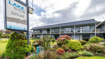 A motel with a signboard, multiple floors, and a well-maintained garden.