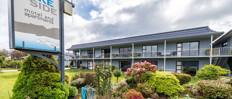A motel with a signboard, multiple floors, and a well-maintained garden.