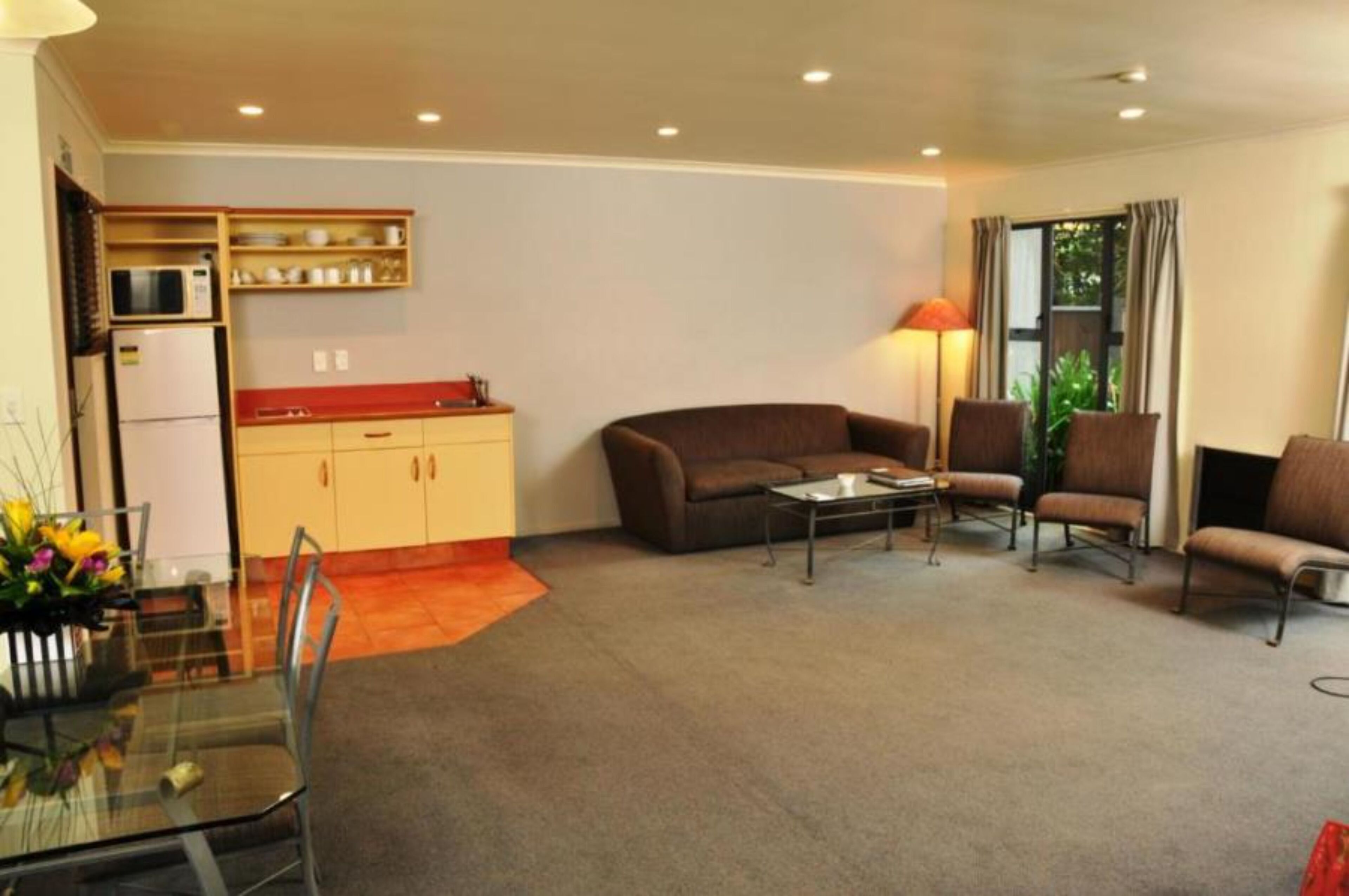A compact living space with a kitchenette, a sofa, a coffee table, and a dining area with a glass table and chairs.
