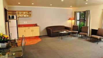A compact living space with a kitchenette, a sofa, a coffee table, and a dining area with a glass table and chairs.