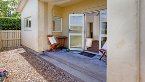 A covered outdoor area with a concrete floor, a wooden fence, and a small table with a chair. - Tuscany on Thames (Thames)