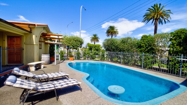 A swimming pool with lounge chairs, a pergola, and a house with a red door. - Tuscany on Thames (Thames)