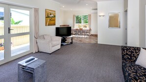 A living room with a sofa, a TV, and a dining area with a table and chairs. - Tuscany on Thames (Thames)