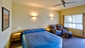A bedroom with a bed, a chair, a desk, and a ceiling fan. - Tuscany on Thames (Thames)