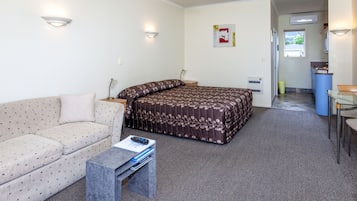 Una habitación con cama, sofá, una mesita y un rincón de cocina.