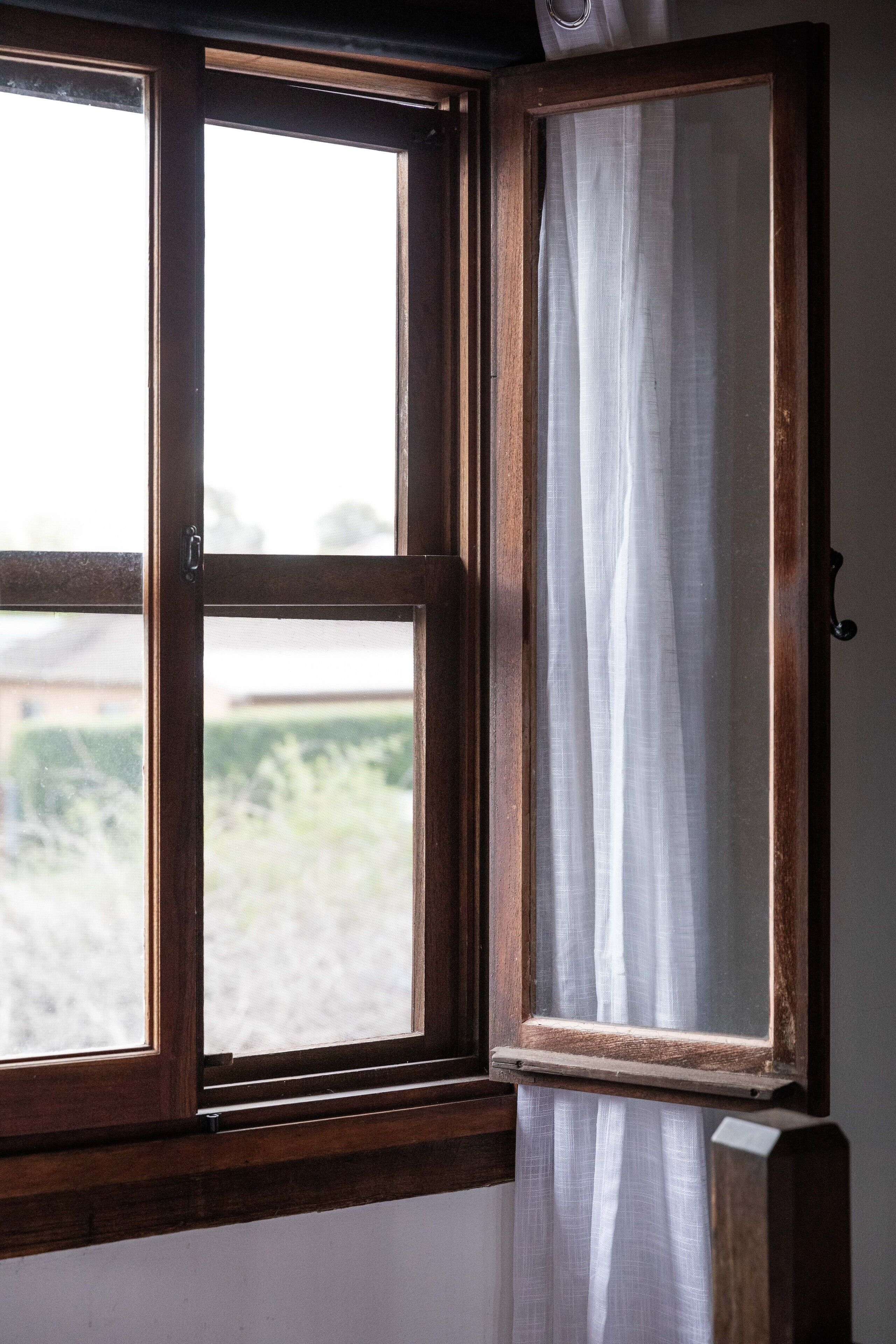 A window with a wooden frame and white curtains.