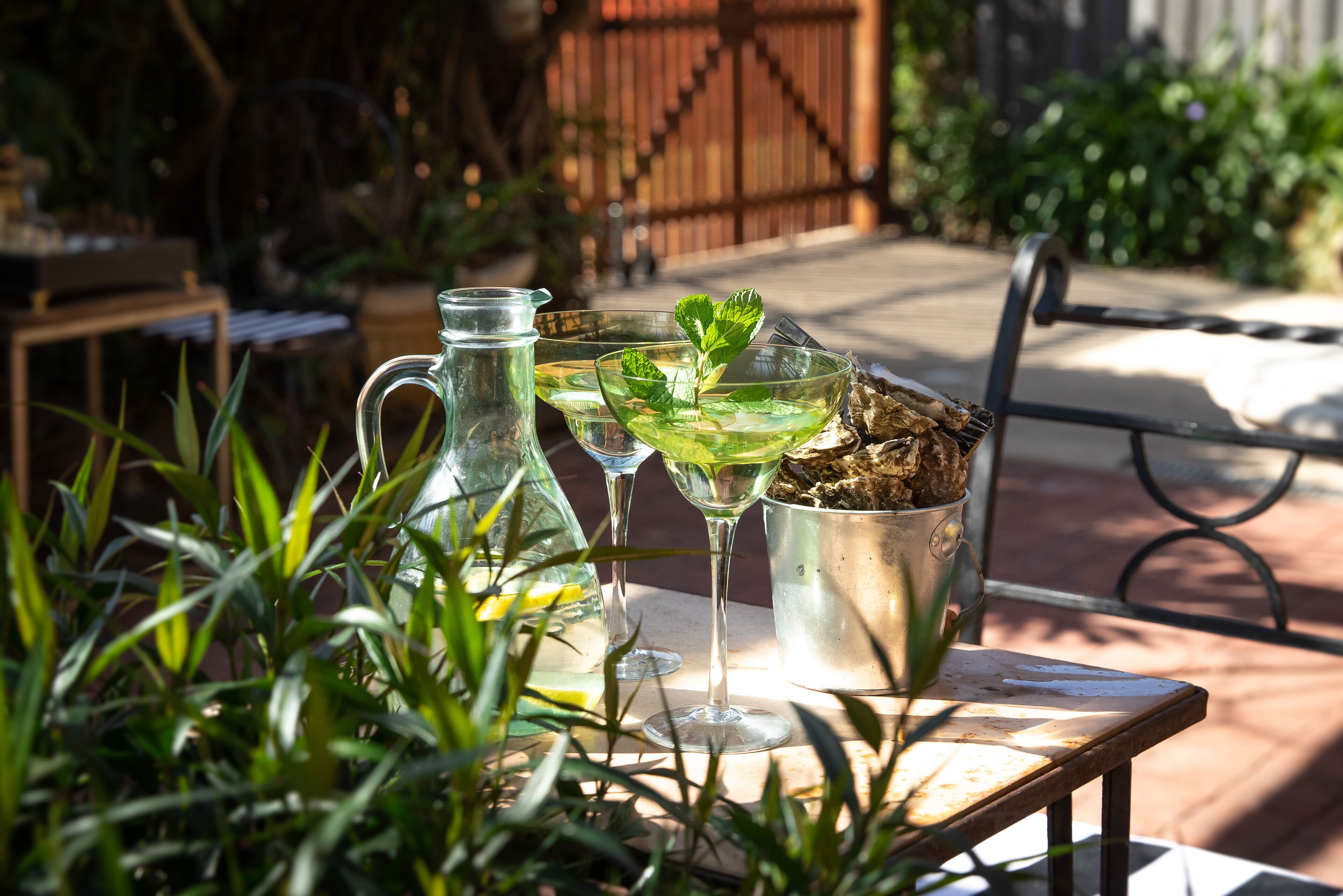 A patio with a table set for drinks, a pitcher, and a bucket.