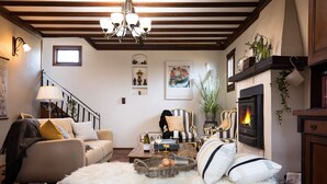 A cozy living room with a sofa, a coffee table, a fireplace, and a staircase. - The Table Guesthouse (Greta)