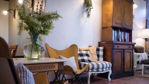 A cozy room with a wooden cabinet, a checkered sofa, a striped chair, and a table with a vase of flowers. - The Table Guesthouse (Greta)