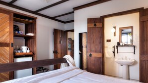 A bedroom with a wooden bed frame, a white mattress, a wooden wardrobe, a white sink, and a mirror. - The Table Guesthouse (Greta)