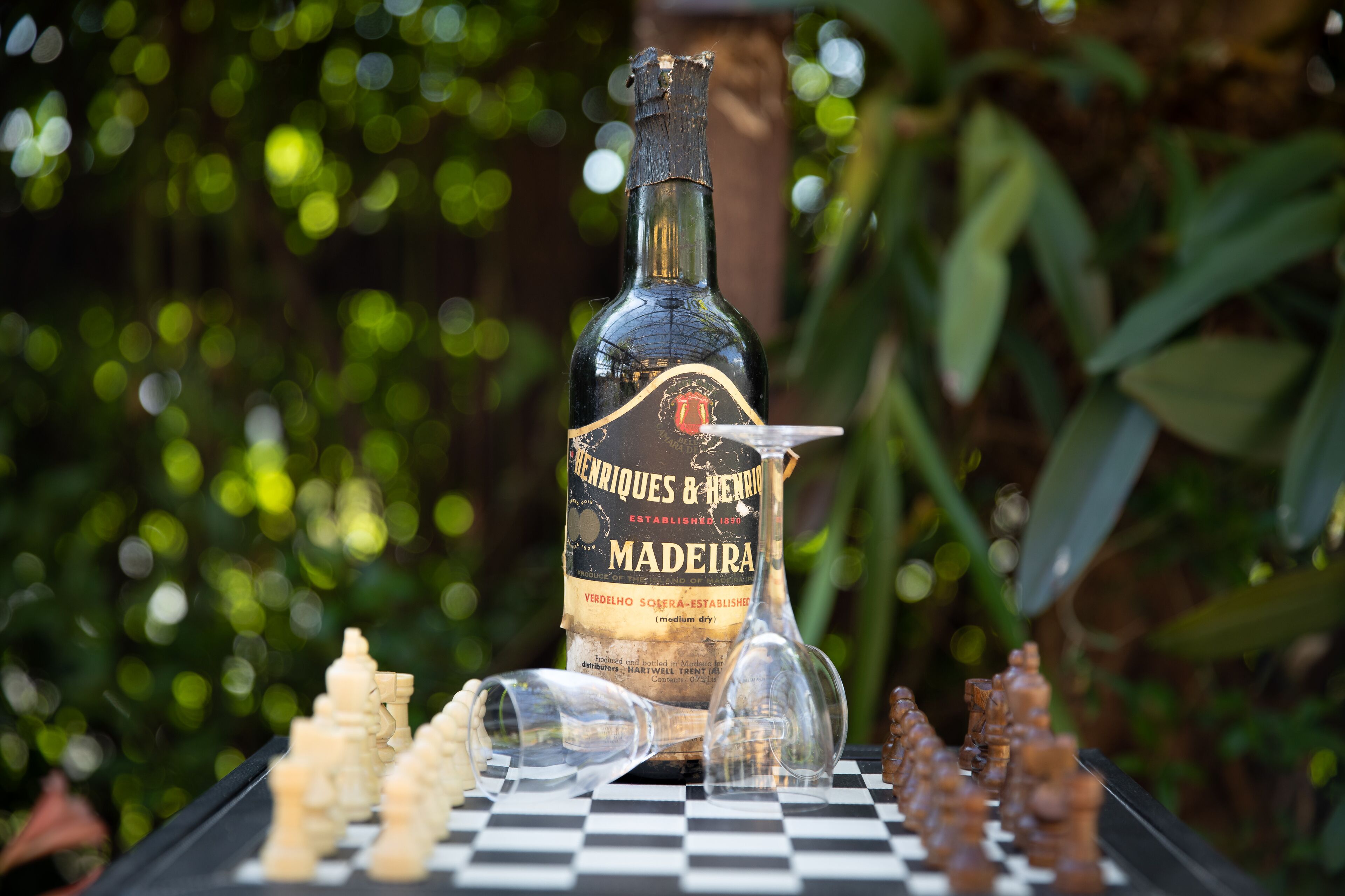 A bottle of Madeira wine on a chessboard with pieces.
