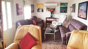 A living room with a sofa, armchairs, a coffee table, and a painting of a cityscape.