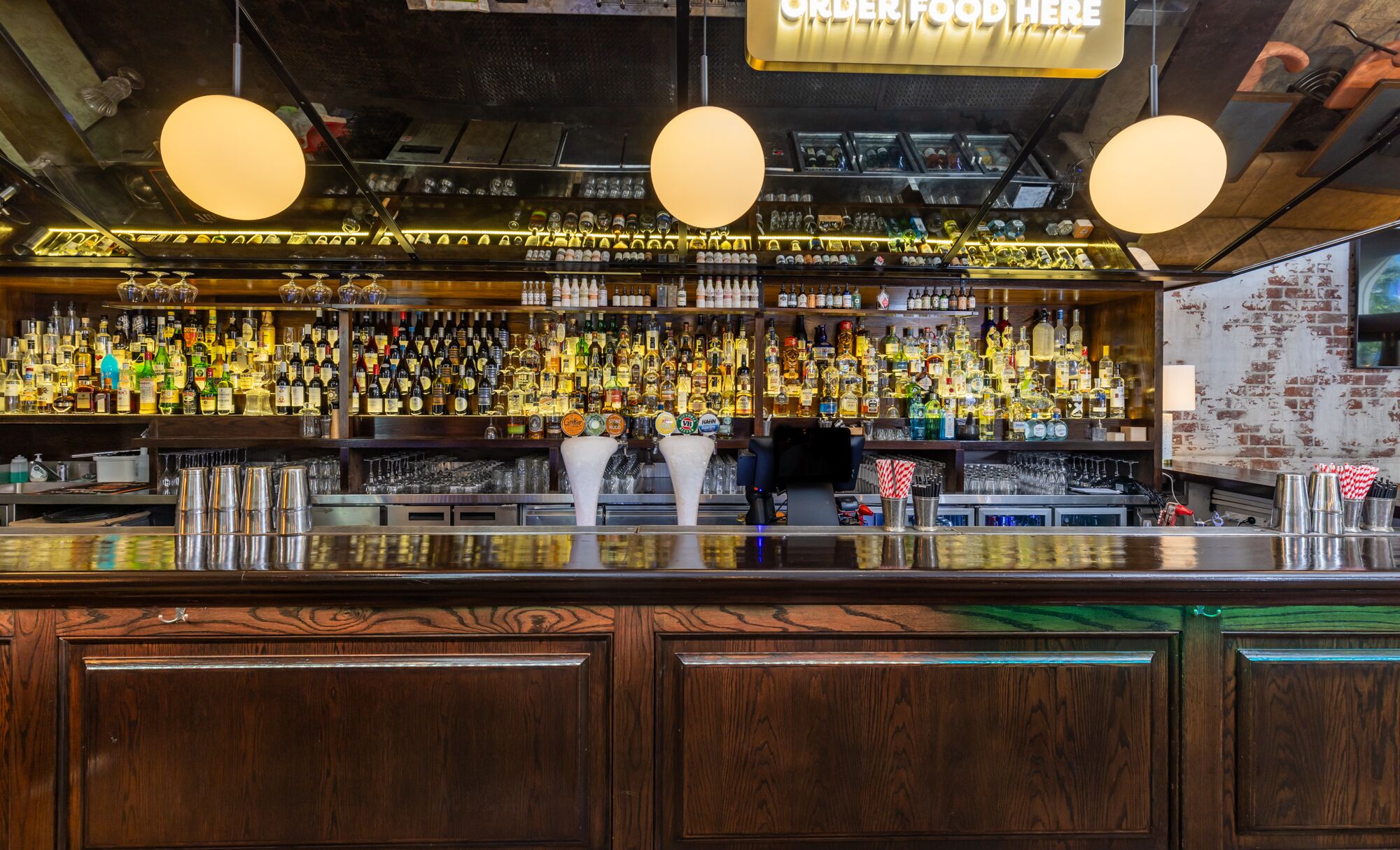 Un bar avec un comptoir en bois et une variété de bouteilles d’alcool.