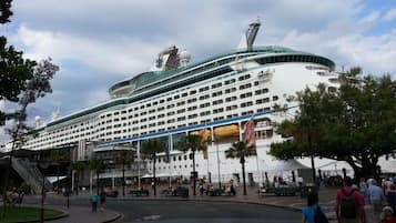 Un gran crucero amarrado en un puerto, con un edificio terminal al frente.