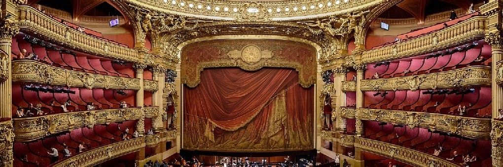 Un interior de teatro ornamentado con asientos en varios niveles y un gran escenario.