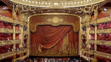 Un interior de teatro ornamentado con asientos en varios niveles y un gran escenario.