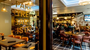 A bar area with tables and chairs, a visible sign reading "PARK STREET BAR & BISTRO", and a patterned floor. - Hotel Coronation (Sydney)