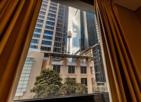 A view from inside a room with a large window overlooking a modern building with multiple floors and a mix of architectural styles.